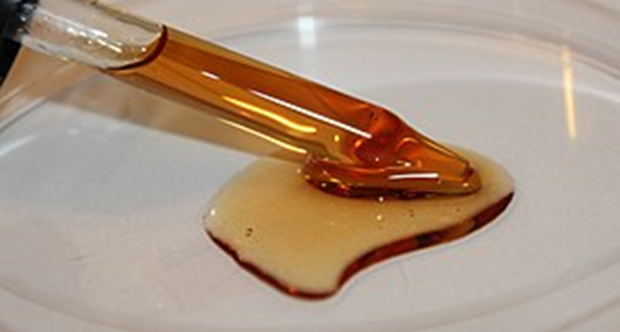 טפטפת עם שמן בגוון חום-אדמדם על צלחת שטוחה.