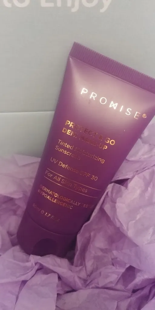 Tube of Promise Protect & Go Demi Make-Up sunscreen resting on purple tissue paper, showcasing its branding and SPF 30 protection features.