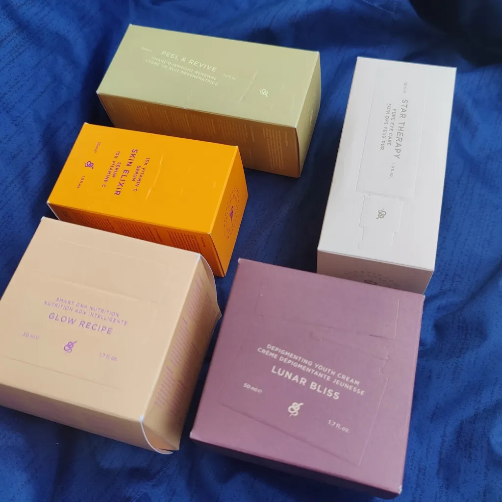 ארבע אריזות קרטון בצבעים שונים המייצגות מוצרים קוסמטיים של המותג ICONIX, מונחות על בד כחול.