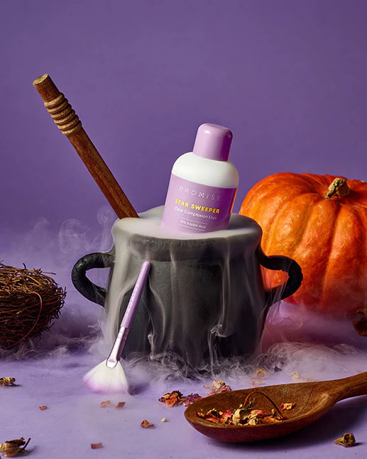 Bottle of Promise Star Sweeper in a cauldron surrounded by a wooden spoon, a pumpkin, and a makeup brush, with smoke effects and a purple background.
